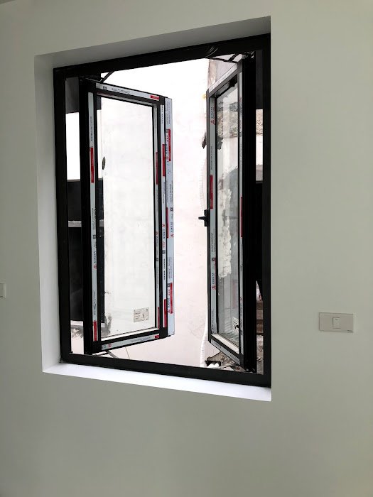 Cửa sổ nhôm kính hai cánh mở quay màu đen lắp trong tường sơn trắng